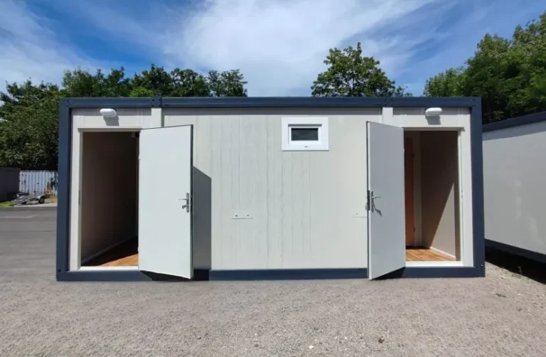 Bürocontainer mit zwei geöffneten Eingangstüren und kleinem Fenster, Seitenansicht im Außenbereich.