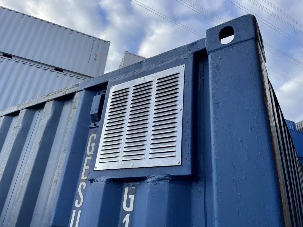 Detailaufnahme eines montierten Lüftungsgitters am Container – stabile Befestigung und präziser Ausschnitt.