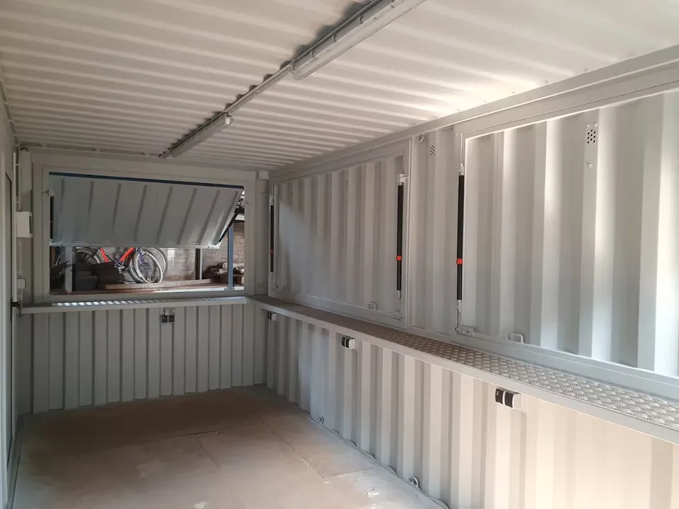 Innenraum eines Bar-Containers mit mehreren Verkaufsklappen und umlaufender Theke